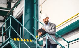 A portrait of an industrial man engineer with clipboard in a factory. Copy space. stock photo A portrait of an industrial man engineer with clipboard in a factory. Copy space. stock photo