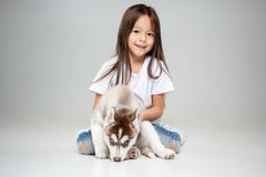 Portrait of a joyful little girl having fun with siberian husky puppy on the floor at studio royalty free stock images Portrait of a joyful little girl having fun with siberian husky puppy on the floor at studio royalty free stock images