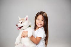 Portrait of a joyful little girl having fun with siberian husky puppy on the floor at studio stock images Portrait of a joyful little girl having fun with siberian husky puppy on the floor at studio stock images