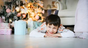 A portrait of a little boy lying on the floor near fir tree stock photos A portrait of a little boy lying on the floor near fir tree stock photos