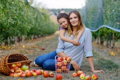 Portrait of little girl and beautiful mother with red apples in organic orchard. Happy woman and kid daughter picking stock photos Portrait of little girl and beautiful mother with red apples in organic orchard. Happy woman and kid daughter picking stock photos