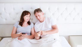 Portrait of loving middle aged couple smiling and watching something on a mobile phone in bedroom stock photo Portrait of loving middle aged couple smiling and watching something on a mobile phone in bedroom stock photo