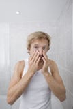 Portrait of man checking for wrinkles on his face in bathroom royalty free stock photos Portrait of man checking for wrinkles on his face in bathroom royalty free stock photos
