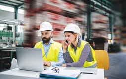 A portrait of an industrial man and woman engineer with laptop in a factory, working. stock image A portrait of an industrial man and woman engineer with laptop in a factory, working. stock image