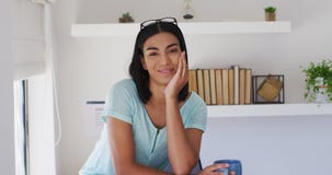 Portrait of mixed race gender fluid person looking at camera and smiling at home