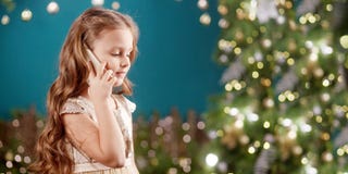 Portrait Of A Smiling Long-haired Little Girl In Dress On Background Of  Lights. Little Girl Talking On The Phone. Christmas, New Stock Photos