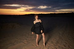 Portrait Of A Young Woman In A Black Dress Walking In The Desert Stock Photo