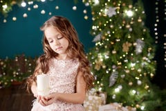 Portrait Of Acute Long-haired Little Girl In Dress On Background Of Lights.Little Girl Holding Burning Candle. Christmas, New Royalty Free Stock Images Portrait Of Acute Long-haired Little Girl In Dress On Background Of Lights.Little Girl Holding Burning Candle. Christmas, New Royalty Free Stock Images