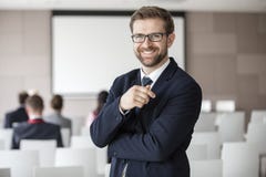 Portrait Of Happy Businessman Standing In Seminar Hall Stock Photos