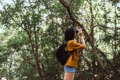 Portrait Of Travel Young Asian Woman Using Binoculars In Forest,Enjoying With Bird Watching Royalty Free Stock Image
