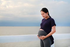 Portrait of pregnant Asian woman embrace her belly standing on seashore at sunset royalty free stock images Portrait of pregnant Asian woman embrace her belly standing on seashore at sunset royalty free stock images