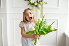 A portrait of a pretty little girl in a white shirt, she is surprised and is holding a bouquet of tulips royalty free stock photo A portrait of a pretty little girl in a white shirt, she is surprised and is holding a bouquet of tulips royalty free stock photo