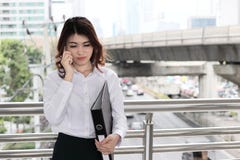 Portrait of pretty young Asian business woman talking on phone at urban city background. stock photo Portrait of pretty young Asian business woman talking on phone at urban city background. stock photo