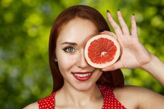 Portrait of a redhead young girl covering her mouth with half a red grapefruit stock photography Portrait of a redhead young girl covering her mouth with half a red grapefruit stock photography