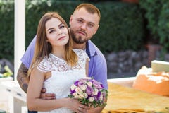 Portrait of a romantic couple against a background of green bushes and trees, girl holding flowers in hands, young beautiful bride Royalty Free Stock Images Portrait of a romantic couple against a background of green bushes and trees, girl holding flowers in hands, young beautiful bride Royalty Free Stock Images