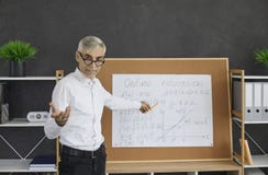 Portrait of senior teacher standing in front of classroom board during online class
