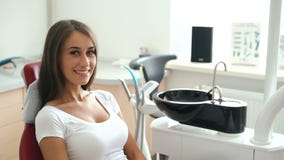 Portrait of girl sitting in dental chair and smiling on the camera. Slowly