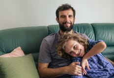 Smiling father and son sitting on their sofa at home stock photography Smiling father and son sitting on their sofa at home stock photography