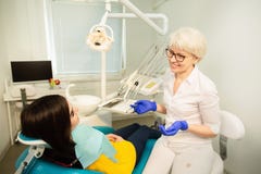 Portrait of a smiling woman, sitting at the dental chair with doctor at the dental office royalty free stock image Portrait of a smiling woman, sitting at the dental chair with doctor at the dental office royalty free stock image