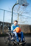 Portrait Of Teenage Boy In Wheelchair Playing Basketball On Outdoor Court