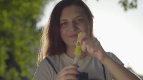 Portrait of the teenage girl in the park blowing soap bubbles at the camera. Cute young woman spending time alone stock video Portrait of the teenage girl in the park blowing soap bubbles at the camera. Cute young woman spending time alone stock video