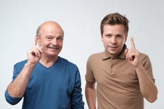 Portrait of two serious mature men father and son with warning finger against light gray background. royalty free stock photo Portrait of two serious mature men father and son with warning finger against light gray background. royalty free stock photo