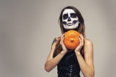 Portrait of woman with halloween skeleton makeup holding pumpkin over gray background stock images Portrait of woman with halloween skeleton makeup holding pumpkin over gray background stock images