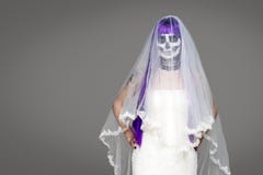 Portrait of woman looks at the camera with terrifying halloween skeleton makeup and purple wig bridal veil, wedding dress over gra stock image Portrait of woman looks at the camera with terrifying halloween skeleton makeup and purple wig bridal veil, wedding dress over gra stock image