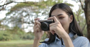 Portrait of young attractive asian woman photographer taking photos in a summer park. stock video Portrait of young attractive asian woman photographer taking photos in a summer park. stock video