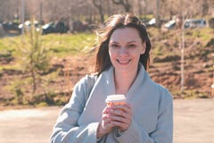 Portrait of young brunette woman in coat walks in city park and drinks coffee. Springtime. royalty free stock photography Portrait of young brunette woman in coat walks in city park and drinks coffee. Springtime. royalty free stock photography