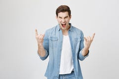 Portrait of young handsome musician screaming and making rock gesture with both hands while enjoying concert. Emotions royalty free stock images Portrait of young handsome musician screaming and making rock gesture with both hands while enjoying concert. Emotions royalty free stock images