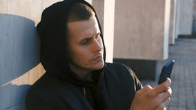 Portrait of young man gangster drug dealer in the hood uses a smartphone outdoor urban background stock video Portrait of young man gangster drug dealer in the hood uses a smartphone outdoor urban background stock video