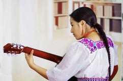 Portrait of young pretty woman wearing beautiful traditional andean clothing, sitting down with acoustic guitar playing royalty free stock images Portrait of young pretty woman wearing beautiful traditional andean clothing, sitting down with acoustic guitar playing royalty free stock images