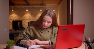 Portrait of young teenage girl writing in notebook being concentrated in office. stock footage Portrait of young teenage girl writing in notebook being concentrated in office. stock footage