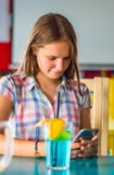 Young teenager brunette girl with long hair sitting indoor in urban cafe, drink a blue lemonade cocktail and use her smartphone royalty free stock image Young teenager brunette girl with long hair sitting indoor in urban cafe, drink a blue lemonade cocktail and use her smartphone royalty free stock image