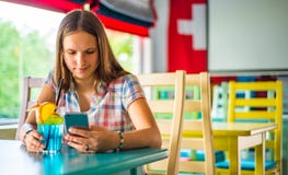 Young teenager brunette girl with long hair sitting indoor in urban cafe, drink a blue lemonade cocktail and use her smartphone royalty free stock photos Young teenager brunette girl with long hair sitting indoor in urban cafe, drink a blue lemonade cocktail and use her smartphone royalty free stock photos