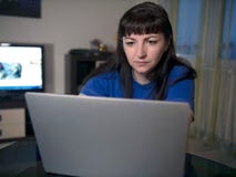 Portrait of young woman working on laptop at home in the evening stock photos Portrait of young woman working on laptop at home in the evening stock photos