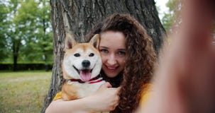 Portret die van aantrekkelijke dame selfie met puppy in park nemen die koesterend hond kussen stock video Portret die van aantrekkelijke dame selfie met puppy in park nemen die koesterend hond kussen stock video