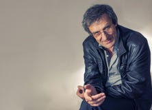 Portret dorosły z włosami mężczyzna siedzi z pytajnym spojrzeniem na krześle w świetle w szkłach - szara koszula i fotografia royalty free Portret dorosły z włosami mężczyzna siedzi z pytajnym spojrzeniem na krześle w świetle w szkłach - szara koszula i fotografia royalty free