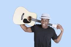 Portret młoda amerykanina afrykańskiego pochodzenia mężczyzna przewożenia gitara nad bławym tłem zdjęcia royalty free Portret młoda amerykanina afrykańskiego pochodzenia mężczyzna przewożenia gitara nad bławym tłem zdjęcia royalty free