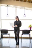 Portret pomyślny bizneswomanu mienia laptop w ona ręki Szczęśliwa piękna ufna kobiety pozycja przy biurem z notatnikiem Obraz Stock Portret pomyślny bizneswomanu mienia laptop w ona ręki Szczęśliwa piękna ufna kobiety pozycja przy biurem z notatnikiem Obraz Stock