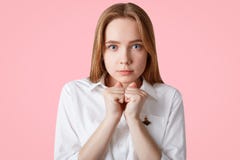 Portret poważna skupiająca się urocza kobieta utrzymuje ręki w pięściach, jest ubranym białą koszula, nadzieję dla coś, odizolowy obrazy stock Portret poważna skupiająca się urocza kobieta utrzymuje ręki w pięściach, jest ubranym białą koszula, nadzieję dla coś, odizolowy obrazy stock