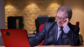 Portret starszy biznesmen w formalnym kostiumowym działaniu z laptopem opiera na ręce męczy w biurze zbiory Portret starszy biznesmen w formalnym kostiumowym działaniu z laptopem opiera na ręce męczy w biurze zbiory