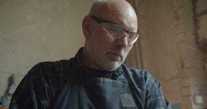 Portret starszy cieśla w ochronnym szkła działaniu w manufakturze jest koncentrujący i poważny zdjęcie wideo Portret starszy cieśla w ochronnym szkła działaniu w manufakturze jest koncentrujący i poważny zdjęcie wideo