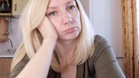 Portret van een droevige en bored jonge blonde vrouwenzitting in keuken, droefheids en depressieconcept stock video Portret van een droevige en bored jonge blonde vrouwenzitting in keuken, droefheids en depressieconcept stock video