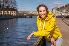 Portret van een jonge vrouw die op een Zonnige dag op een de lentestraat door de rivier glimlachen royalty-vrije stock fotografie Portret van een jonge vrouw die op een Zonnige dag op een de lentestraat door de rivier glimlachen royalty-vrije stock fotografie