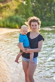 Portret van een moeder en haar weinig zoon op een zandige rivierbank op een hete de zomerdag stock foto Portret van een moeder en haar weinig zoon op een zandige rivierbank op een hete de zomerdag stock foto