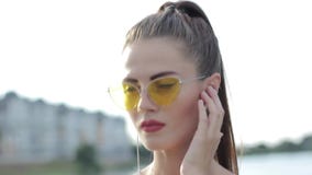 Portret van een mooi sportenmeisje in hoofdtelefoons en met een telefoon stock video Portret van een mooi sportenmeisje in hoofdtelefoons en met een telefoon stock video