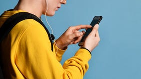 Portret van een vrolijke student die rugzak, in GLB en glazen dragen en smartphone over purpere achtergrond gebruiken stock fotografie Portret van een vrolijke student die rugzak, in GLB en glazen dragen en smartphone over purpere achtergrond gebruiken stock fotografie