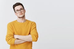 Portret van ernstig-kijkt knappe en slimme jonge mens die in glazen en gele sweater met ongeloof kijken en stock foto Portret van ernstig-kijkt knappe en slimme jonge mens die in glazen en gele sweater met ongeloof kijken en stock foto